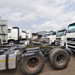 Row of white Volvo FM 400 6x4 truck tractors parked in dealership yard, multiple units available for immediate delivery